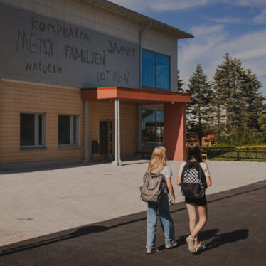 Två flickor är på väg till skolan med ryggsäckar på ryggen.