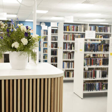 En vit blombukett på ett bord. I bakgrunden syns bibliotekets bokhyllor.