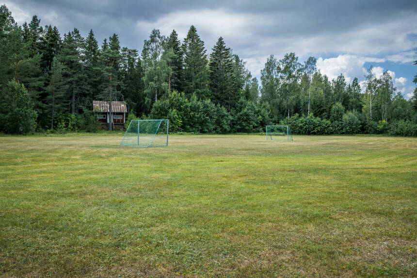 Kaksi jalkapallo maalia luonnon nurmikentällä metsätaustalla.