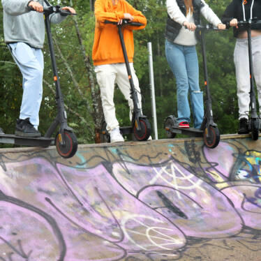 Fyra ungdomar med sina sparkbräden på kanten till en skateramp.