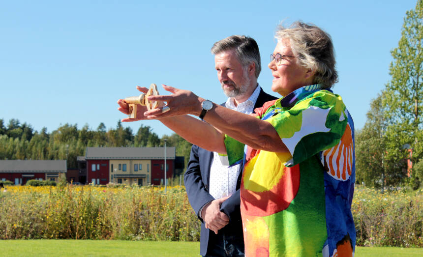 Merja Laaksonen sträcker fram Sjundeås nyckel. I bakgrunden  Anders Ahlskog.